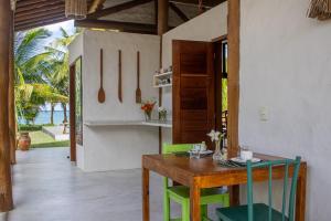 a dining room with a wooden table and green chairs at Casa Caroá - Chalé 3 in Japaratinga