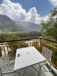 a white table and chairs on a balcony with a view at Nomad House in Manāli