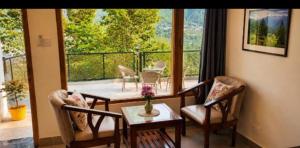 a living room with a table and chairs and a balcony at Nomad House in Manāli