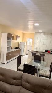 a living room with a couch and a table and a kitchen at Casa Espaçosa e Aconchegante com 4 camas, 3 quartos in Juazeiro do Norte