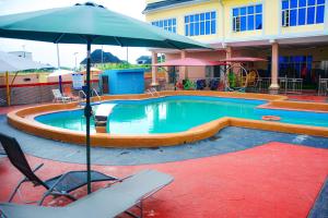 a pool with an umbrella and chairs and a playground at 6A Resort LTD in Owerri