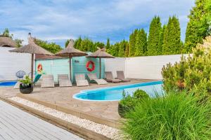a backyard with a swimming pool with chairs and umbrellas at Sea You Stegna in Stegna