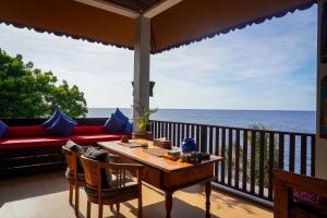 a balcony with a table and a couch and the ocean at Villa Kampung Kecil Beach Front in Kubu
