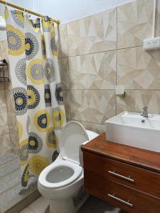 a bathroom with a toilet and a sink and a shower curtain at ACOGEDOR DEPa CON GARAGE PRIVADO in Nueva Loja