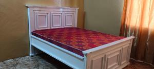 a white bed with a red bedspread on it at Michenzani rooms apartment in Ngambo