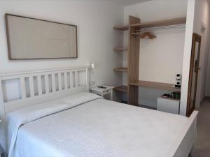 a bedroom with a white bed and a large screen at La LLar in Carboneras