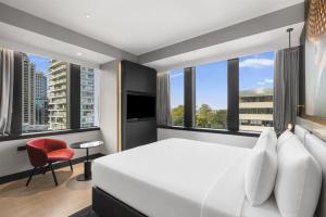 a bedroom with a white bed and a red chair at Radisson RED Auckland in Auckland +88 photos
