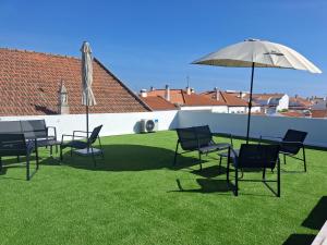 a group of chairs and an umbrella on a lawn at Várzea Alojamentos Turísticos in Vila Nova de Milfontes