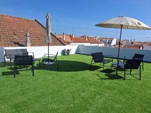 a group of chairs and an umbrella on a lawn at Várzea Alojamentos Turísticos in Vila Nova de Milfontes