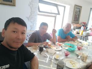 three men sitting at a table eating food at Alima in Ottuk