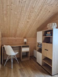 a desk and chair in a room with a wooden ceiling at Domek pod Wierzbami in Leleszki