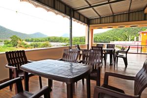 a restaurant with tables and chairs and a large window at Malar Resort in Wodapatti