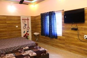 a bedroom with a bed and a flat screen tv at Malar Resort in Wodapatti