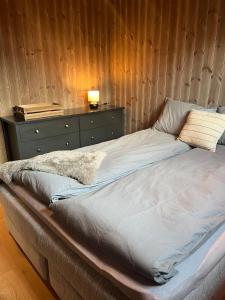 a large bed in a bedroom with a wooden wall at New! Mountain apartment close to Hardangervidda in Eidfjord