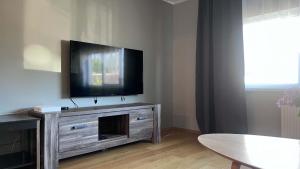 a living room with a flat screen tv on a entertainment center at Viskoosa Näkmani Apartment in Kõrgessaare