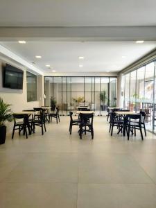 a large room with tables and chairs and windows at Das Nações Hotel in Florianópolis