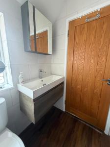 a bathroom with a sink and a wooden door at One Bed Flat Close to Station & River in Reading