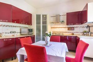 a kitchen with red chairs and a table with a vase of flowers at stanza a casa marina in Rosolina