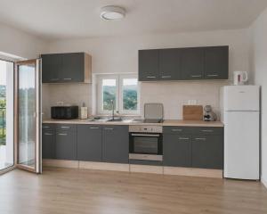 a kitchen with black cabinets and a white refrigerator at Apartma PERIN in Dobrovo