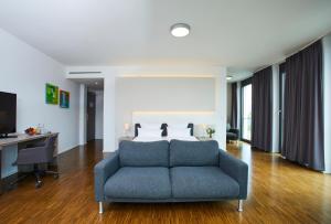 ein Wohnzimmer mit einer blauen Couch vor einem Bett in der Unterkunft Hella Globe in Lippstadt