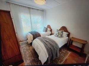 a bedroom with two beds and a window at At Let Se Plek in Jeffreys Bay