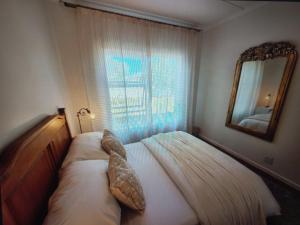 a bedroom with a bed with a mirror and a window at At Let Se Plek in Jeffreys Bay