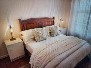 a bedroom with a large bed with white sheets and pillows at At Let Se Plek in Jeffreys Bay