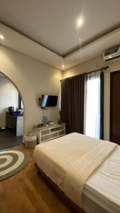 a bedroom with a bed and a tv and a window at Defano Villa Klotok in Yogyakarta