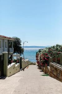 a walkway next to the ocean with flowers and a building at Stella's Apartment in Karfas