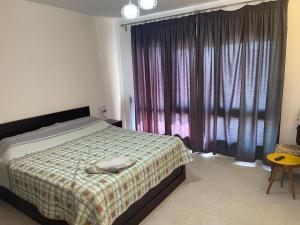 a bedroom with a bed and a window with curtains at Swanlake north coast in Zāwiyat al ‘Awwāmah