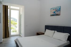 a bedroom with a white bed and a window at Hotel Riviera Dhermi in Dhërmi
