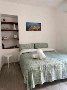 a bedroom with a bed with a green blanket at Casa Zia Maria in Pollina