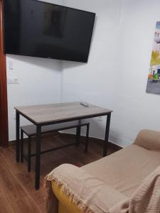 a living room with a table with a tv on the wall at Alojamientos Capri in Quesada
