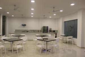 a room with tables and white chairs and a kitchen at Heaven By O in Unawatuna