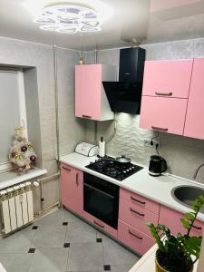 a pink kitchen with a stove and a sink at Comfort VV in Volodymyr-Volynskyi