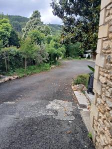 an empty road next to a stone house at Gîte Uros Terrasse avec spa in Le Bugue +2 photos