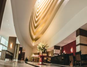 a lobby with a large ceiling and a table and chairs at Hotel Dunamys Curitiba in Curitiba