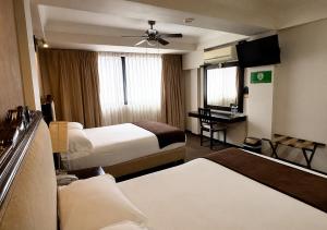 a hotel room with two beds and a ceiling fan at Hotel Clara Luna in Xalapa