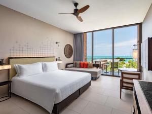 a bedroom with a bed and a view of the ocean at Pullman Khao Lak Resort in Khao Lak