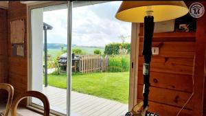 a lamp in a room with a view of a yard at La Cour des Miracles Gîte in Sequehart +4 photos