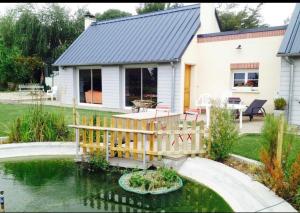 a house with a wooden deck over a pond at La Cour des Miracles Gîte in Sequehart