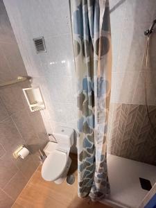 a bathroom with a toilet and a shower curtain at Pensión El Alamo in Lepe