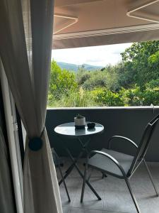 a table and chairs on a balcony with a window at Anna rooms ANTHOS GROUP in Nea Vrasna