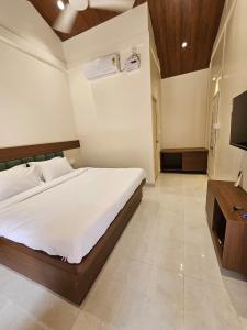 a bedroom with a bed and a flat screen tv at Saavi Resort Shrivardhan in Srīvardhan