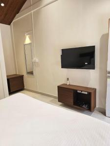 a bedroom with a bed and a flat screen tv at Saavi Resort Shrivardhan in Srīvardhan +6 photos