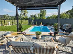 a patio with a swimming pool with chairs and a pergola at Dovolenkový domček in Sabinov