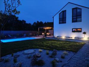 a house with a yard with a swimming pool at night at Dovolenkový domček in Sabinov +5 photos