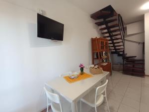 a dining room with a white table and a tv on a wall at Casa Orchidea in Villasimius
