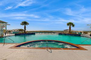 a swimming pool with turquoise water and palm trees at Point West Resort in Galveston