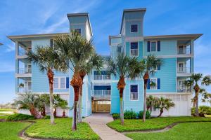a blue building with palm trees in front of it at Point West Resort in Galveston